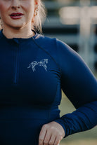 A person wearing a Pure Canter Motion Top Long - Navy with a geometric horse design on the chest, showcasing premium base layers that are both quick-drying and moisture-wicking.